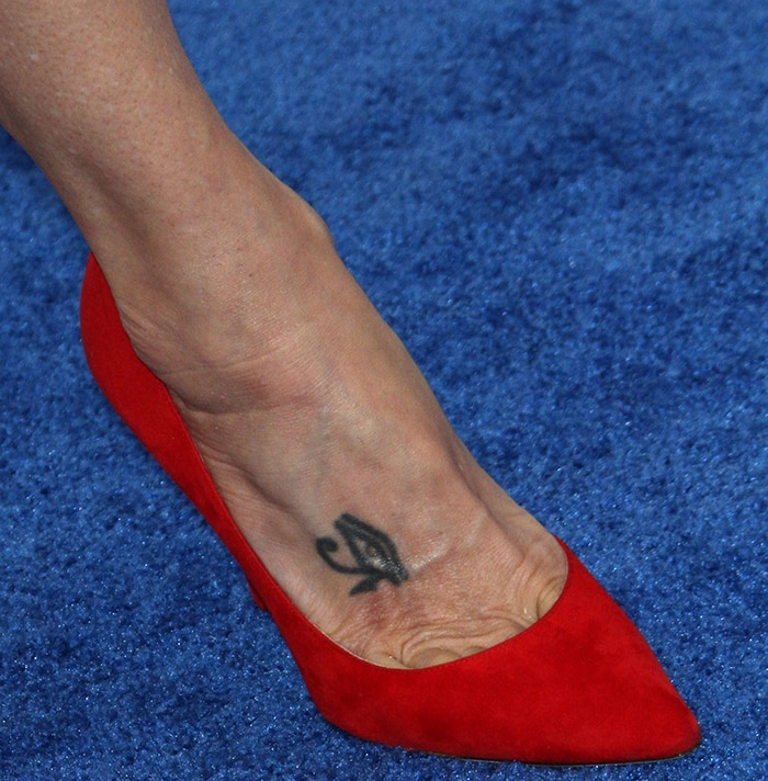 Marisa Tomei reveals her Eye of Horus foot tattoo in vibrant red suede pointed-toe pumps, the bold color and clean silhouette drawing attention to the symbolic ink along her inner foot