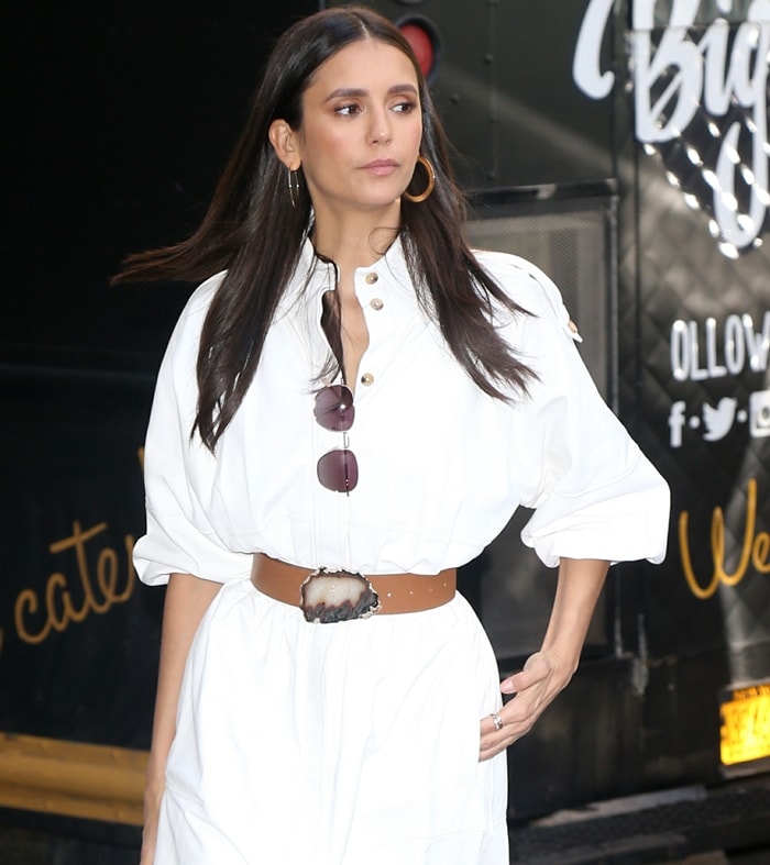 Rounded Kate Young x Tura sunglasses, Jennifer Fisher Baby Drew hoop earrings, and a wide leather belt with a sculptural agate-style buckle added warm contrast to Nina Dobrev's minimalist white ensemble