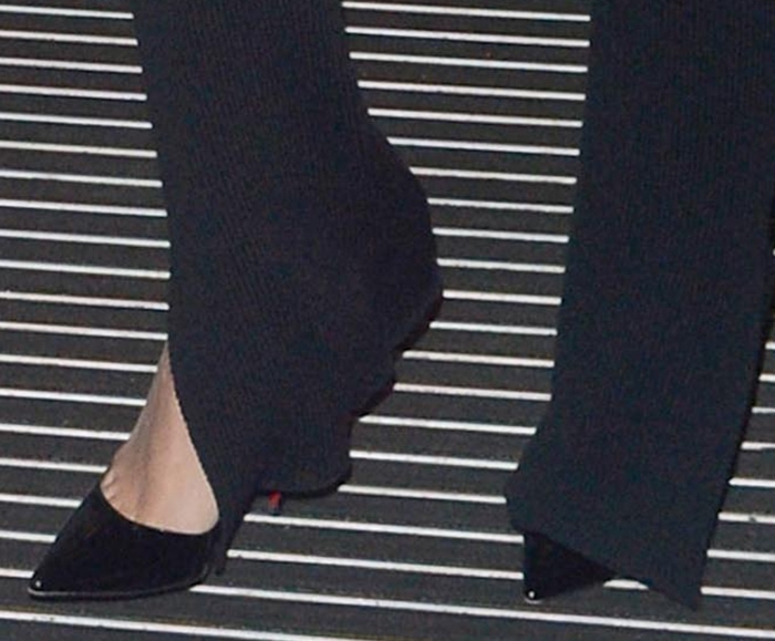 Rita Ora steps out in black patent Christian Louboutin So Kate pumps, the razor-sharp pointed toe and towering stiletto peeking out beneath rib-knit trousers