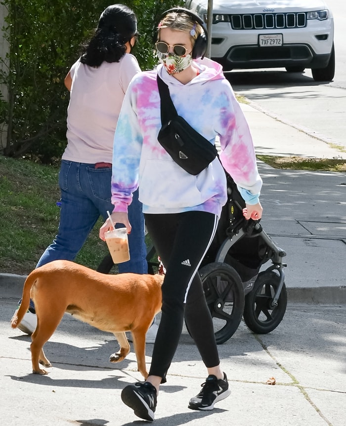 Emma Roberts wearing a floral face mask with a pastel tie-dye hoodie and Prada belt bag