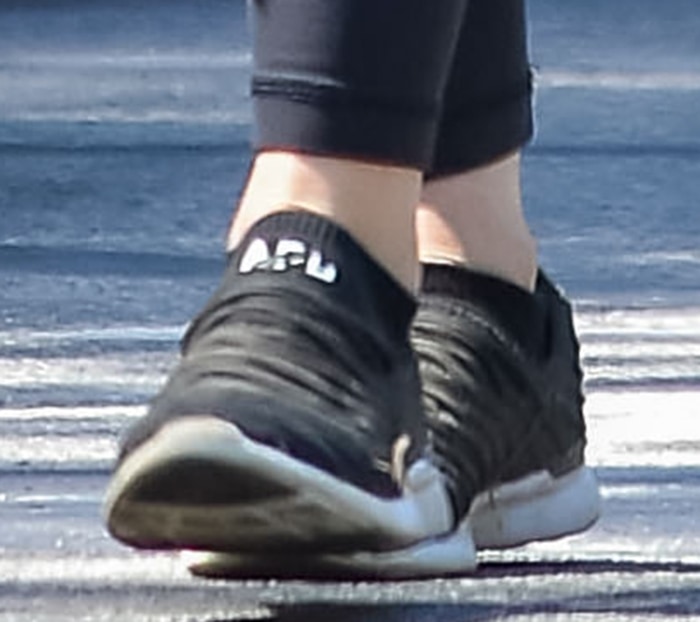 A close-up of Lucy Hale's black APL TechLoom Breeze sneakers highlights the lightweight slip-on design and cushioned Propelium sole that made the luxury trainers a celebrity favorite