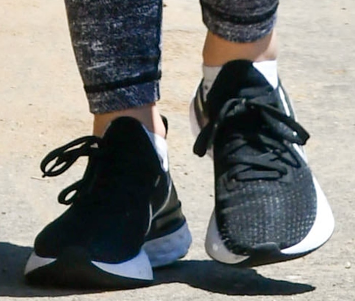 A close-up of Lucy Hale's black-and-white Nike Renew Run sneakers highlights the lightweight mesh upper and sculpted dual-density foam midsole that made the everyday trainer a popular choice for casual workouts and neighborhood walks
