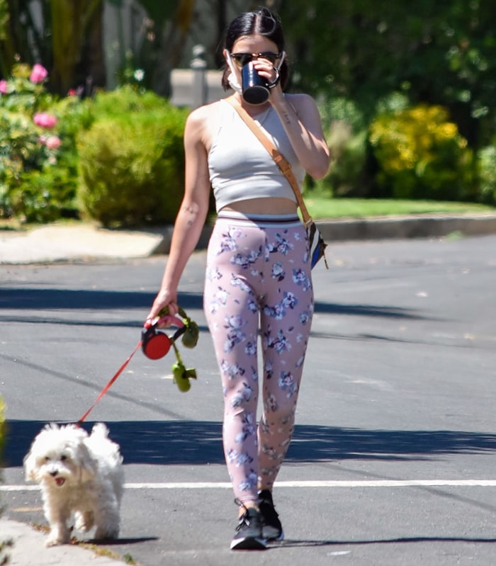 Lucy Hale takes her Maltipoo Elvis for a morning walk in Los Angeles, pairing floral Beyond Yoga "Olympus" leggings with lightweight APL TechLoom Wave sneakers and a minimalist ribbed crop top