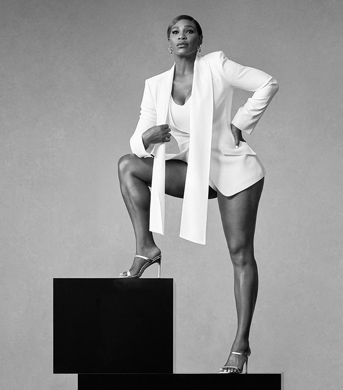 Serena Williams exudes confidence in a sleek white blazer and Stuart Weitzman metallic heels, embodying timeless elegance and power