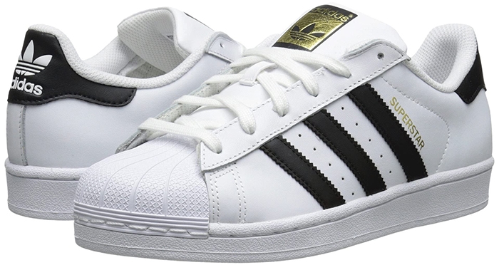 The Adidas Superstar sneaker in white leather with black three-stripe detailing and signature shell toe remains a timeless staple of casual, street-ready style