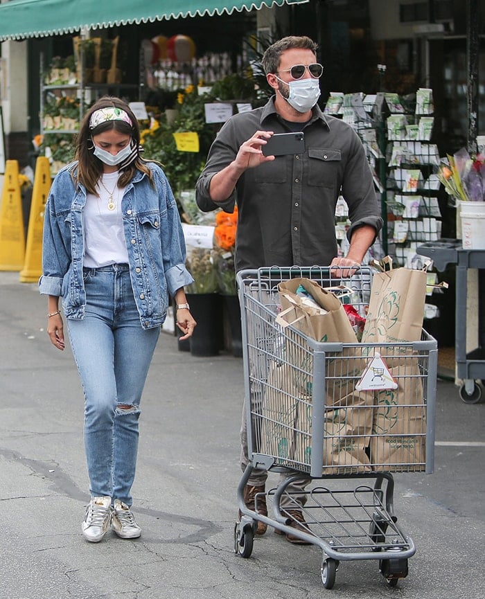 Ana de Armas pairs a floral headscarf and double-denim outfit with scuffed Golden Goose Superstar sneakers, layering Foundrae jewelry with a Cartier watch and Love bracelet for a polished take on casual grocery-run style