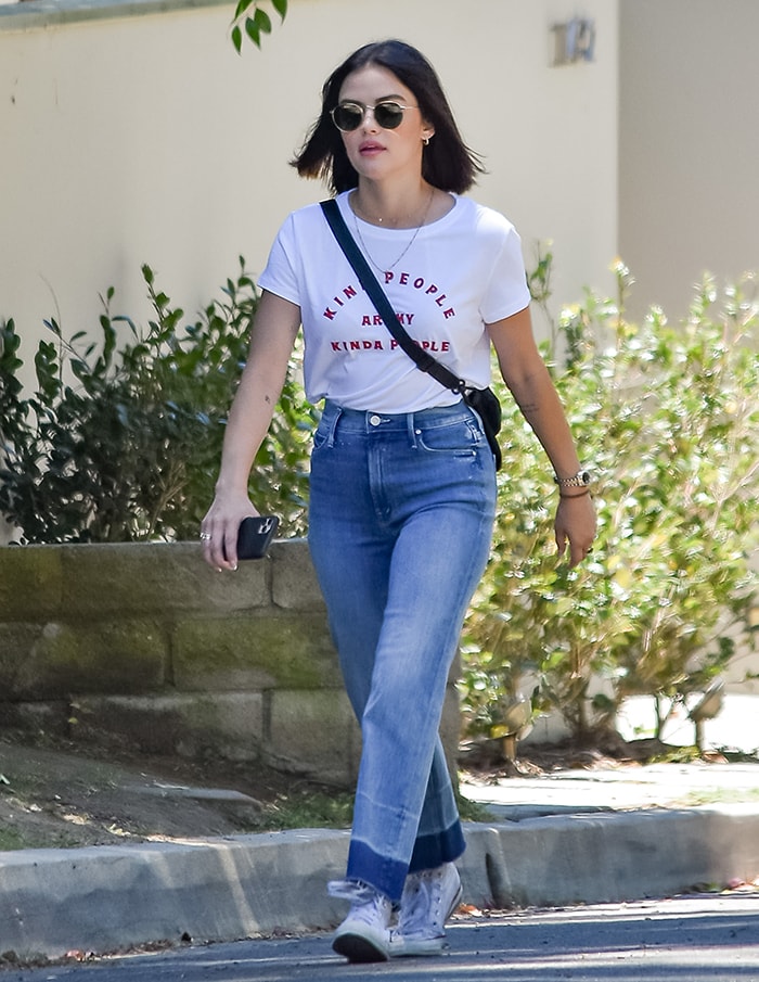 Lucy Hale effortlessly pairs her All Good Feels statement tee with high-waisted Mother denim jeans, finishing the look with classic Converse Chuck Taylor sneakers and chic Ray-Ban Phantos sunglasses for a laid-back yet polished street-style ensemble