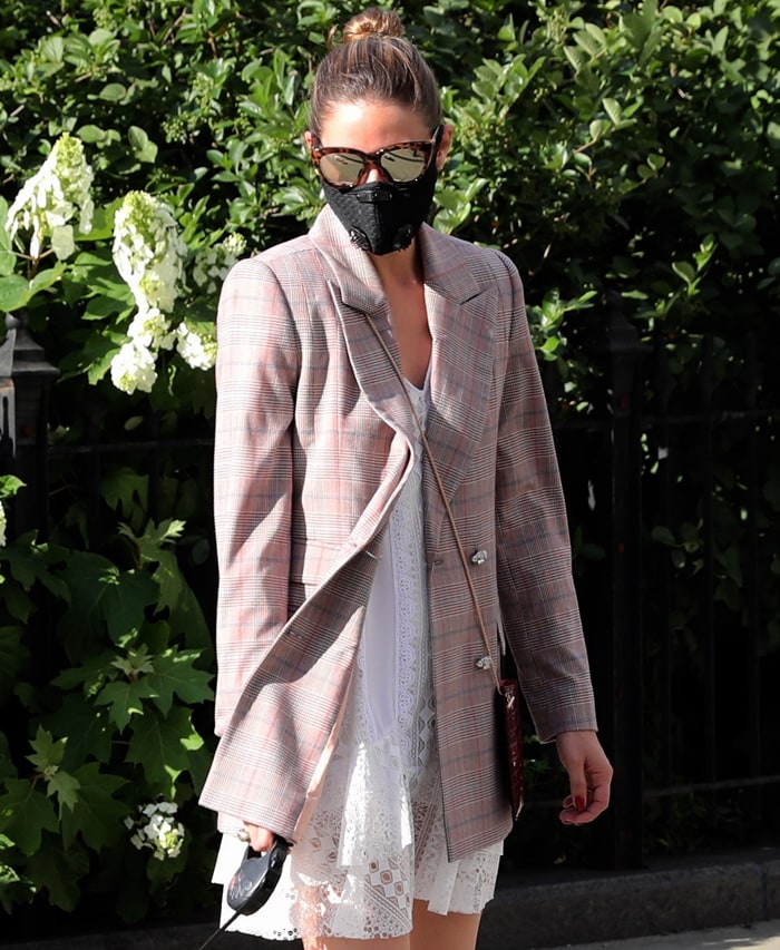 Olivia Palermo elevates her daytime look with a tailored plaid blazer, white lace dress, and oversized sunglasses, finished with a sleek face mask
