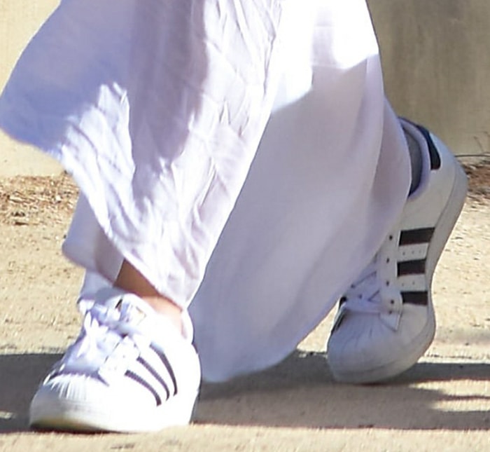 A closer look at Olivia Wilde’s off-duty footwear reveals classic white Adidas Superstar sneakers, grounding her flowing maxi skirt in timeless, laid-back street style