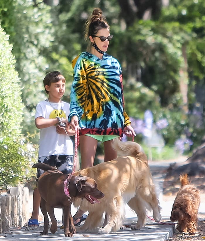Alessandra Ambrosio walks with her son Noah in a tie-dye hoodie and black Havaianas flip-flops