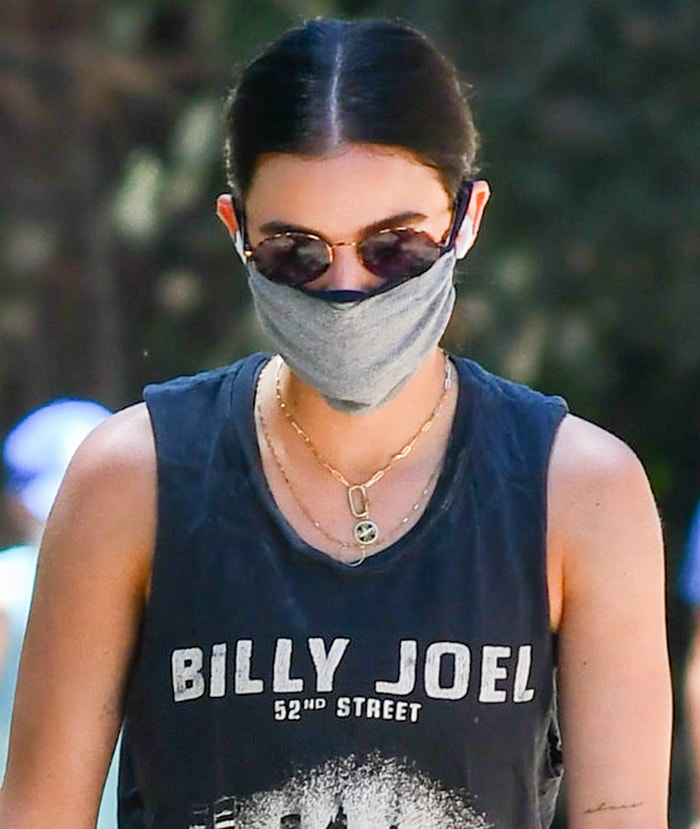Lucy Hale finished her hiking outfit with layered gold necklaces, round Reality Helsinki sunglasses, and a gray cloth face mask, adding understated accessories to the casual workout-inspired look