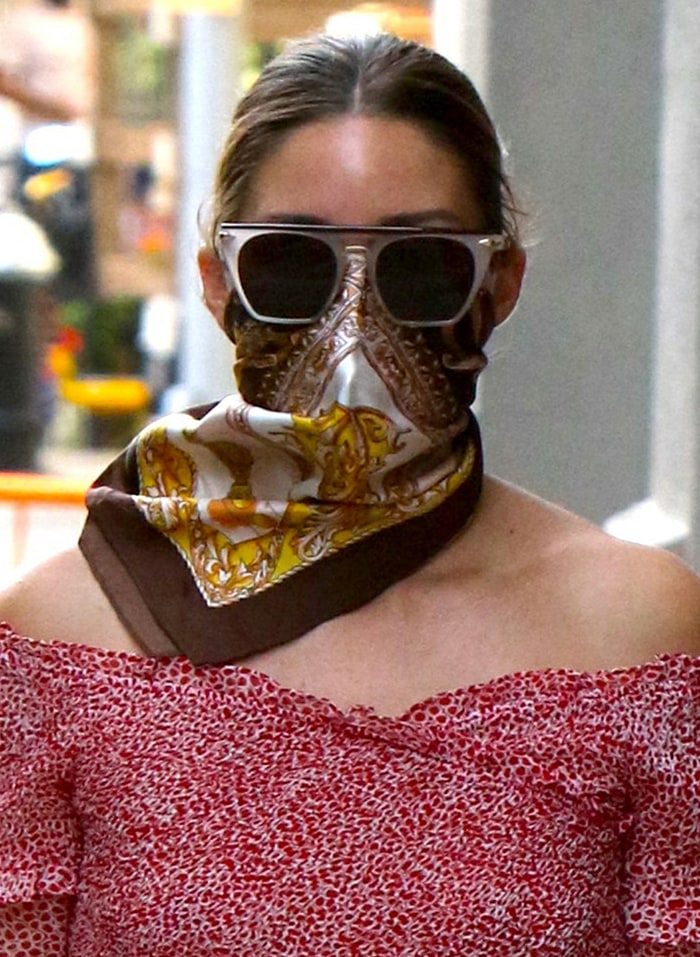 Olivia Palermo accessorizes her printed Lucy Paris outfit with a scarf, sunglasses, jewelry, and a white bucket bag
