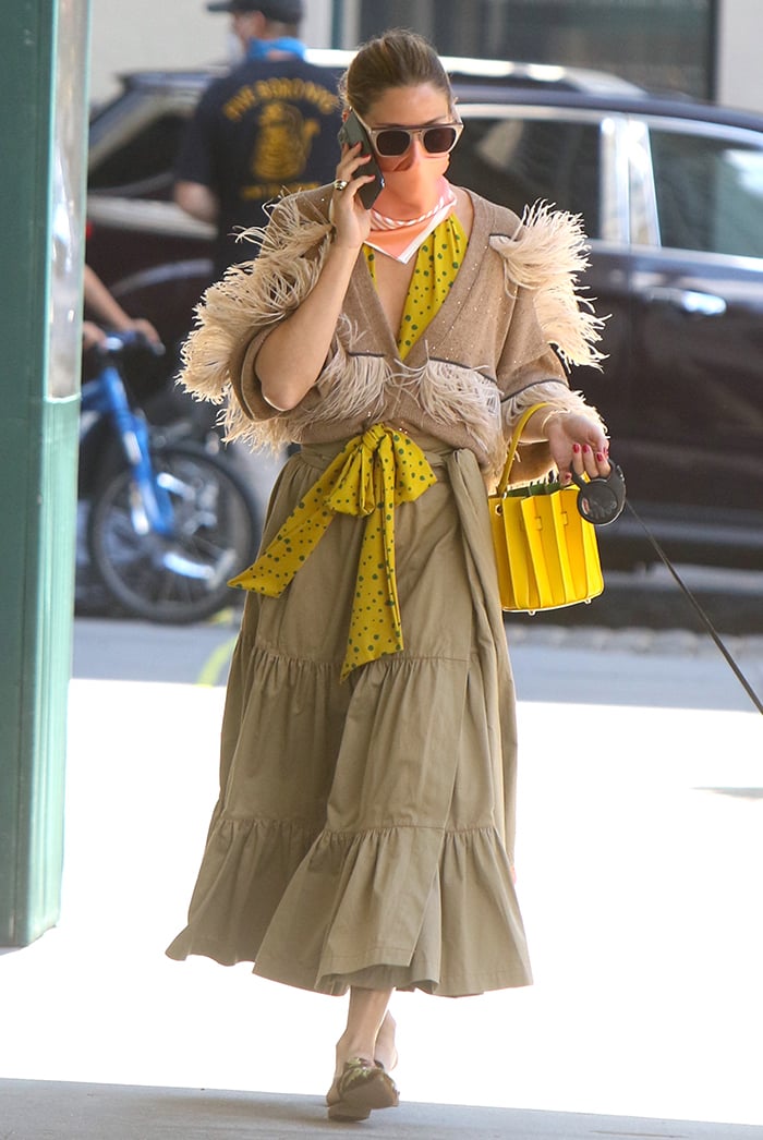 A feather-trimmed Brunello Cucinelli cardigan, sunny polka-dot blouse, and bright yellow bucket bag transform a simple dog walk into a lesson in confident color mixing