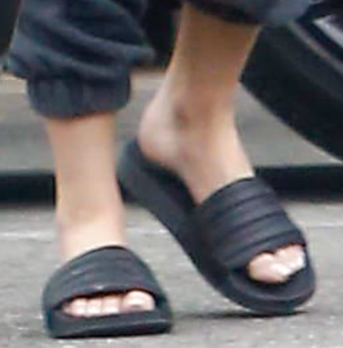 Ashley Benson keeps her off-duty look effortless in black Adidas Adilette Comfort slides, pairing the cushioned sporty sandals with relaxed joggers and a Saint Laurent biker jacket for a classic Los Angeles street-style formula