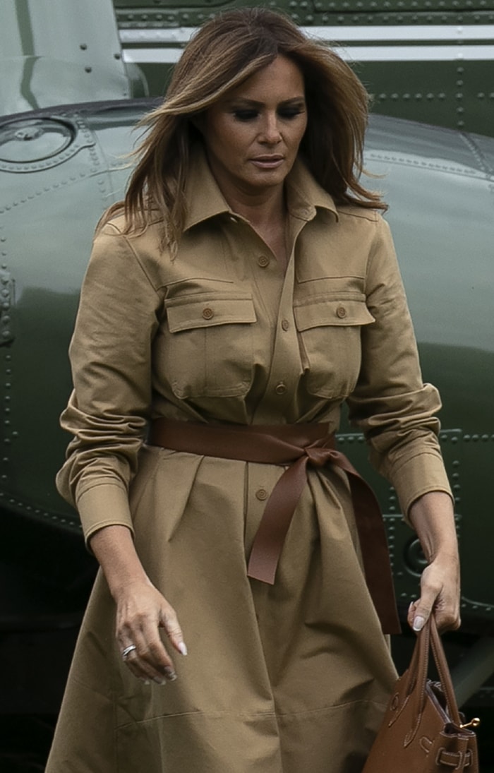 Stepping off the helicopter in a safari-inspired beige shirtdress cinched with a wide brown leather belt, she completed the polished travel look with a matching Hermès Birkin