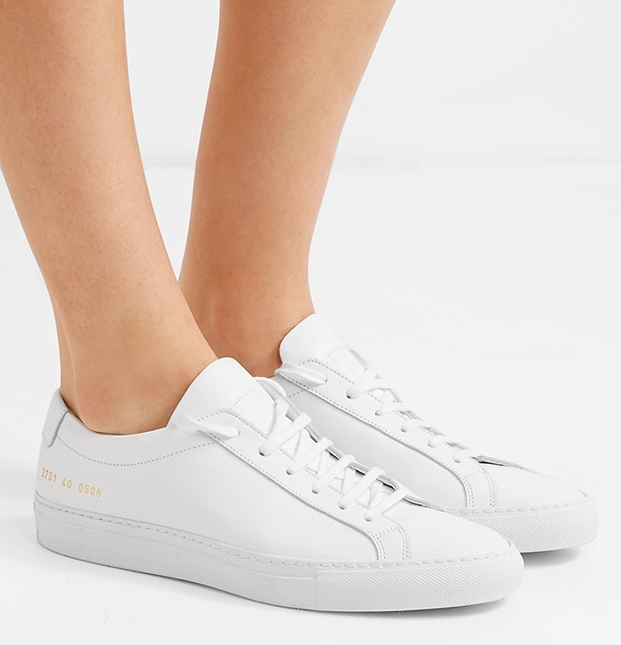 Common Projects Achilles Low sneakers in smooth white Italian leather, finished with the brand’s signature gold serial stamp and a clean, low-profile silhouette that defines modern minimalist luxury