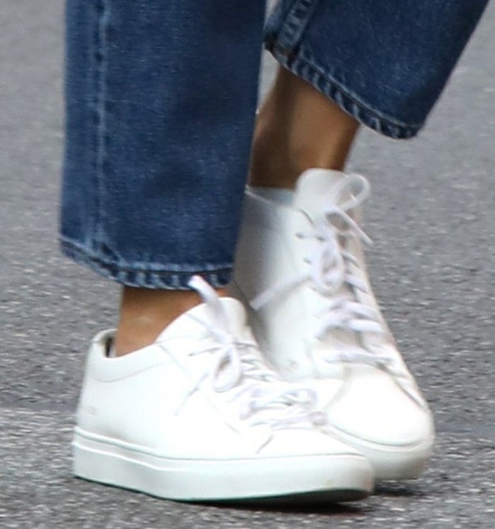 A close-up reveals her sleek white Common Projects Achilles sneakers, their clean lines and low-profile silhouette reinforcing the outfit’s understated, modern appeal