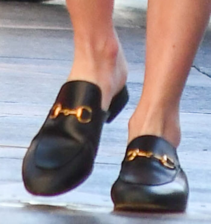 Emma Roberts wears black leather Gucci Princetown slippers with gold horsebit hardware