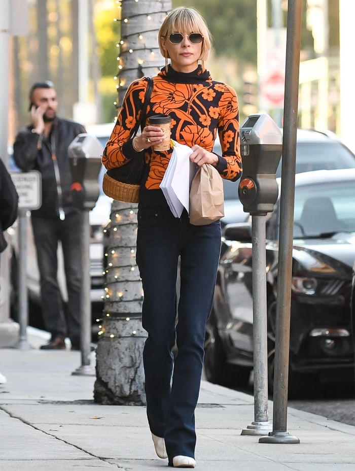 Jaime King steps out in Los Angeles on January 22, 2020, wearing a bold orange floral sweater, flared dark jeans, and pointed-toe white boots that add a sleek finish to her retro-chic look