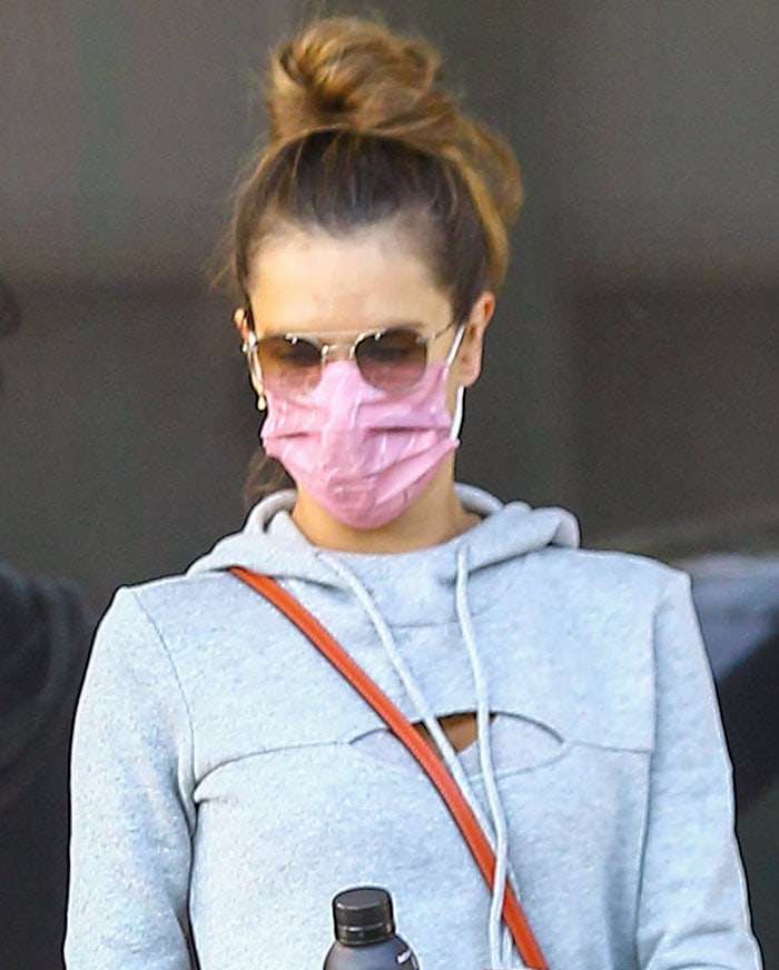 Alessandra Ambrosio balanced sporty layering with polished accessories, pairing a sculpted gray hoodie with aviator sunglasses and delicate gold jewelry