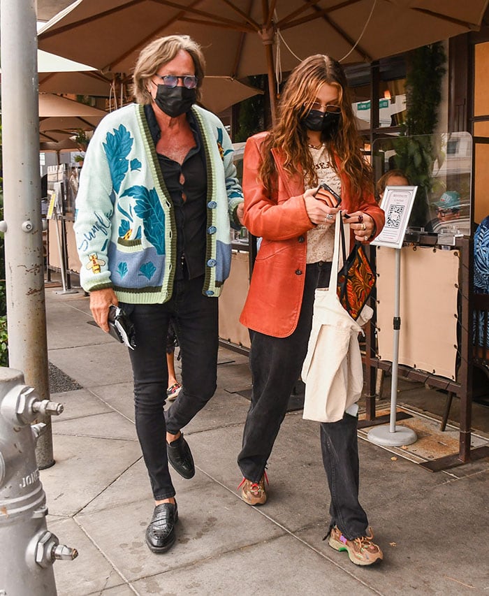 Bella Hadid pairing a coral leather jacket and baggy black jeans with New Balance x Stray Rats 827 “Sewer Stompers” sneakers