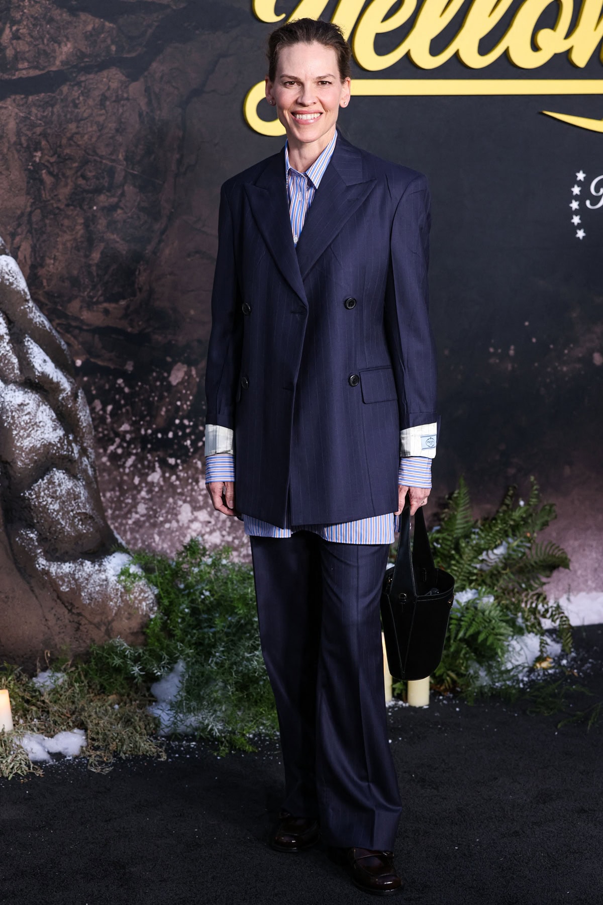 Hilary Swank adds a sharp, androgynous edge in a pinstripe navy suit styled with chunky oxblood loafers and a structured black tote at Showtime’s Yellowjackets FYC Event on April 10, 2025