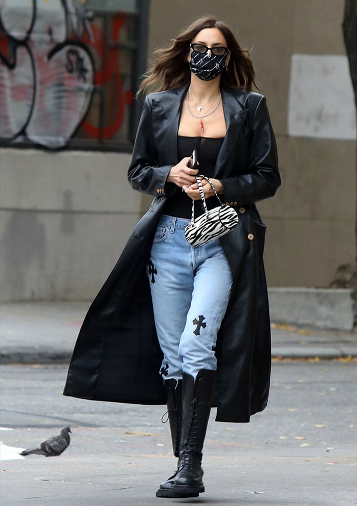 Irina Shayk looks chic in a Nanushka black faux leather trench coat, black corset, and patchwork jeans