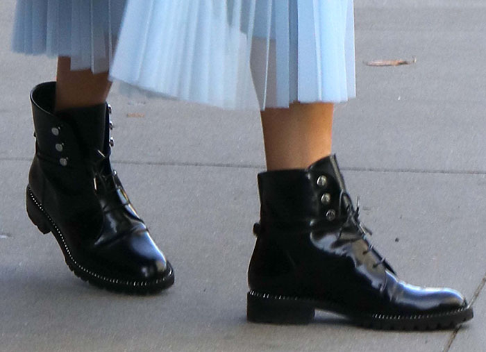 A close-up reveals the Dior Rebelle combat boots’ black patent leather, silver-tone studs, lace-up construction, and low block heels