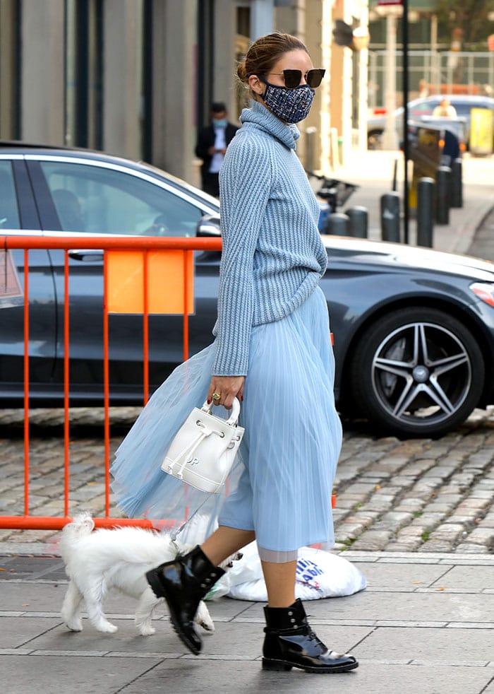The airy movement of Olivia Palermo’s pleated blue skirt contrasts with the structured patent leather and studded soles of her Dior Rebelle boots