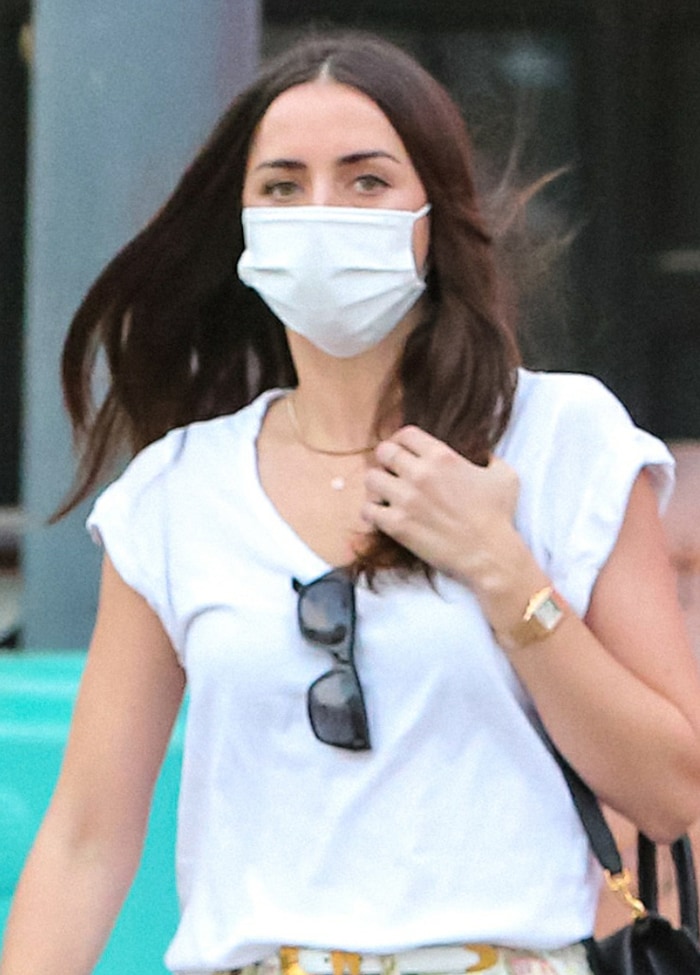 Ana de Armas accessorizes her casual shopping look with a Panthère de Cartier watch, delicate jewelry, sunglasses, and a white Wakamono face mask