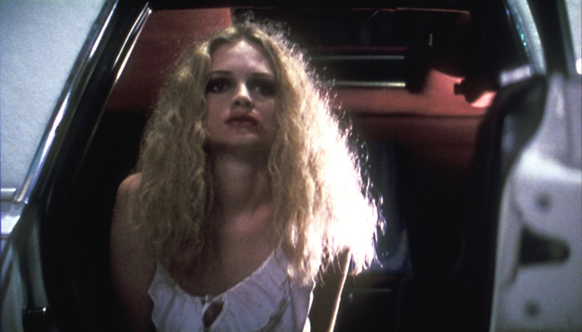 Heather Graham delivers a haunting performance as Rollergirl in Boogie Nights (1997), captured here stepping out of a car with wild curls and a distressed expression that reflect the darker undercurrents of her character's journey