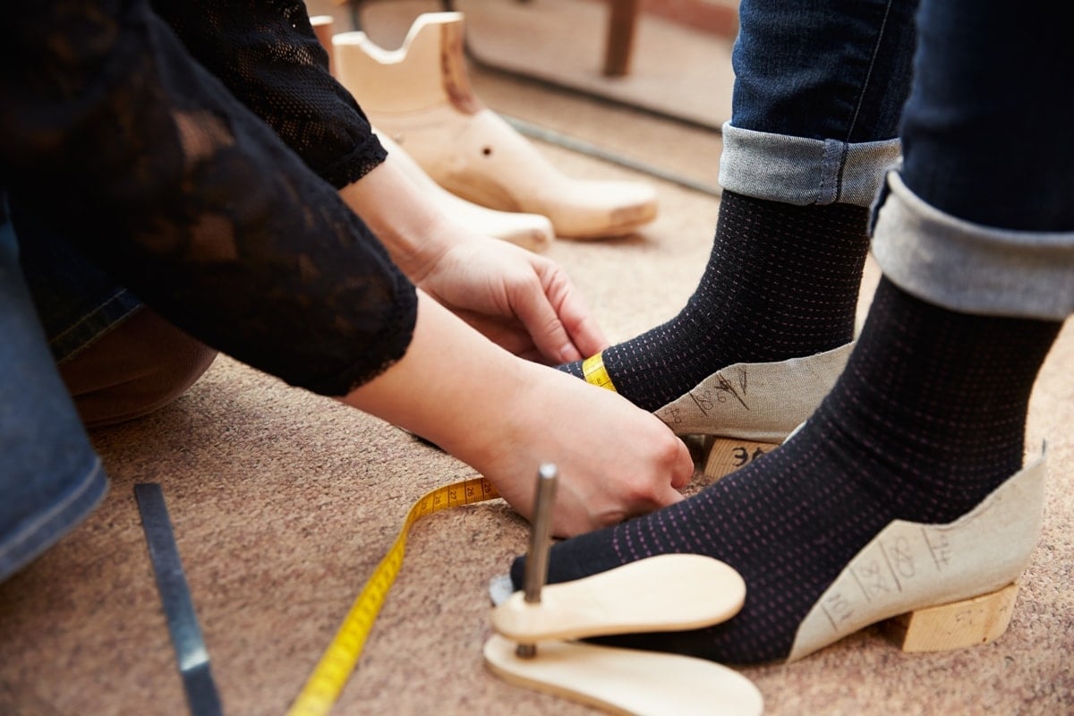 A professional shoe fitting measures both foot length and width, helping determine the correct shoe size and whether a wide or extra-wide fit is needed