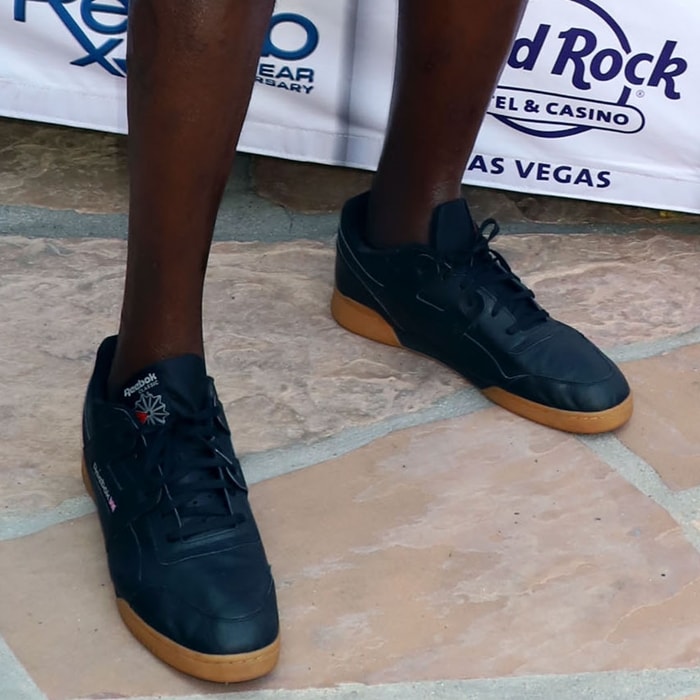 Shaquille O’Neal shows off his enormous Reebok sneakers—custom-sized around US 22 to 23—to accommodate his 7′1″ frame and signature athletic build