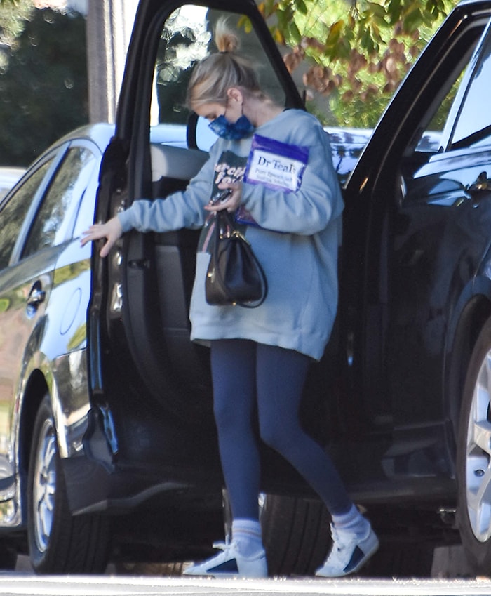 Pregnant Emma Roberts keeps her errand look grounded in comfort with Rothy’s color-block sneakers, pairing the eco-friendly flats with leggings, an oversized sweatshirt, and a printed blue Barrière face mask