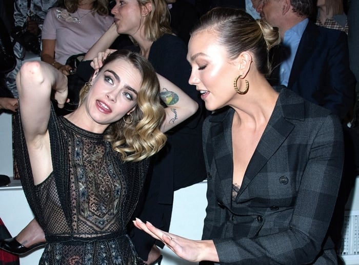 Cara Delevingne stuns in a lace black dress while Karlie Kloss looks chic in a plaid blazer dress as they enjoy the Dior show during Paris Fashion Week