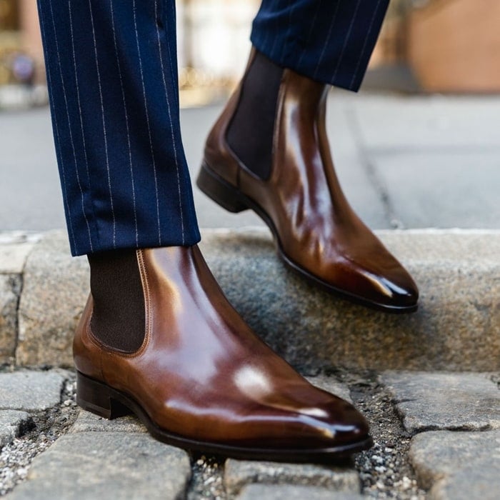 Paul Evans’ polished brown leather Chelsea boots deliver sophisticated elegance, pairing seamlessly with tailored pinstripe trousers for a sharp, elevated look