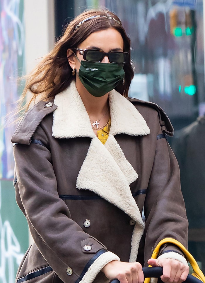 A closer look reveals her oversized shearling-trimmed coat, slim sunglasses, and layered gold jewelry, balancing softness and structure in a cold-weather street style moment