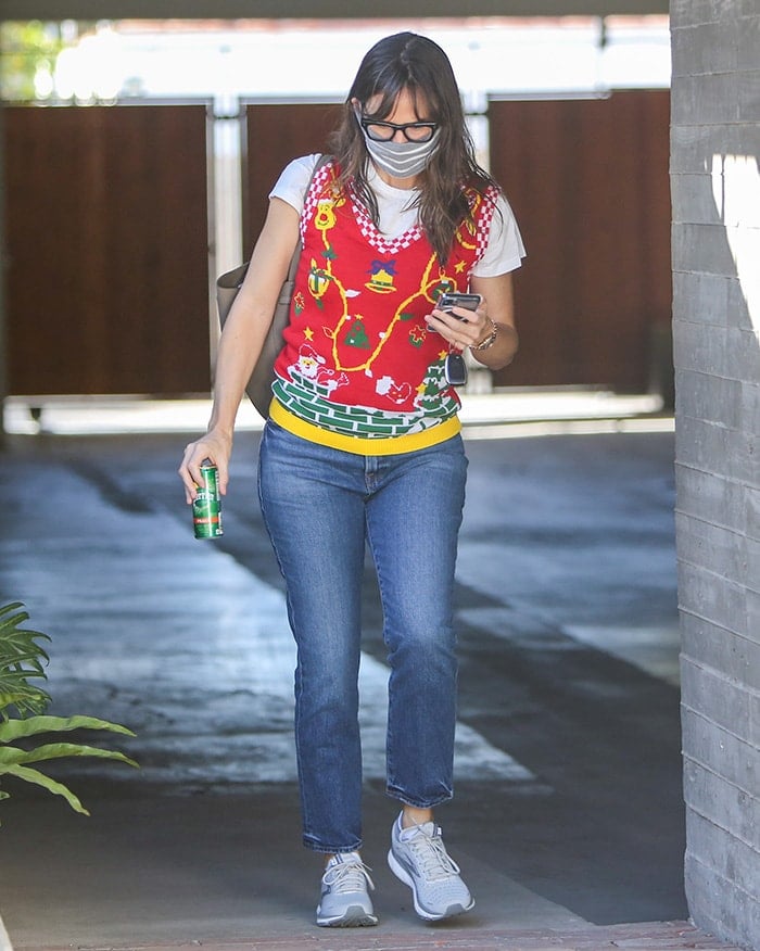 Jennifer Garner embraces festive flair in a playful $17 V28 Christmas sweater vest layered over a white tee, paired with cropped boot-cut jeans and comfy Brooks Ghost 13 sneakers as she leaves her Brentwood office on December 18, 2020