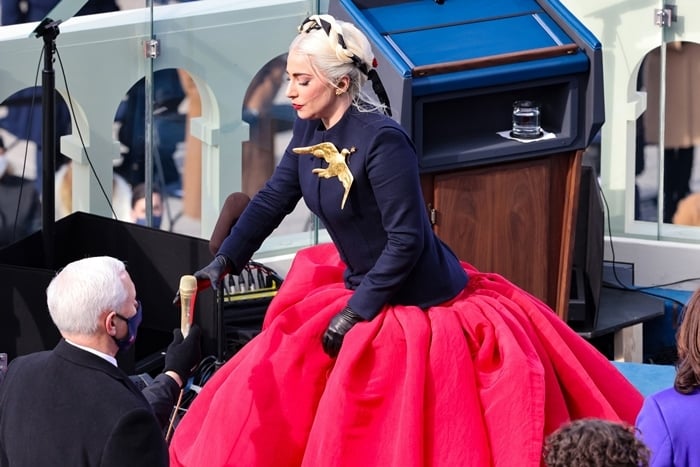 As Vice President Mike Pence looks on, Lady Gaga grabs a golden microphone to sing the national anthem of the United States