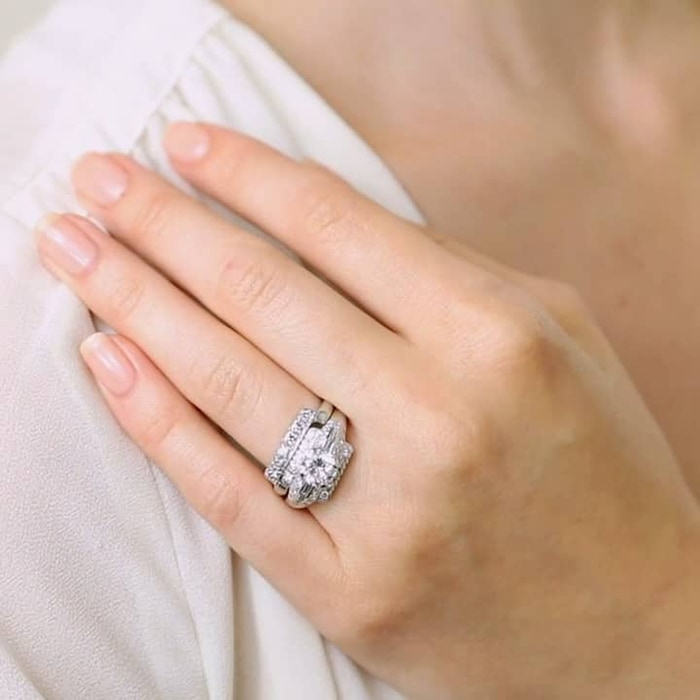 A 1950's ring with a classic Art Deco geometry featuring a 1.20-carat bright white round brilliant cut diamond, two double rows of single cut diamonds and a row of baguettes
