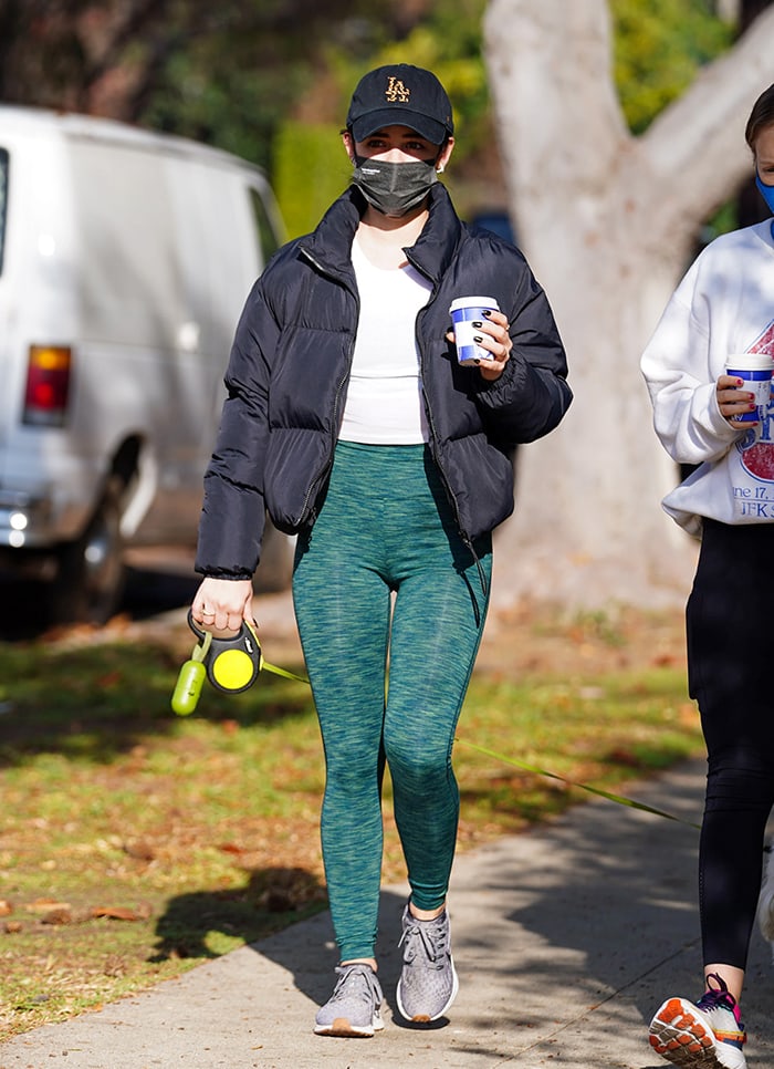 Hale keeps her dog-walking uniform streamlined in green leggings and Nike running shoes, adding a cropped navy puffer and simple white tee