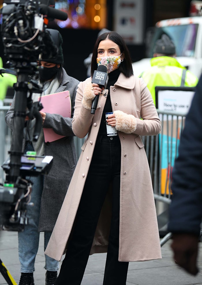 In New York, Hale trades workout layers for a tailored beige Dolce Gabbana coat over a black turtleneck and dark bootcut jeans while filming a New Year’s Eve segment