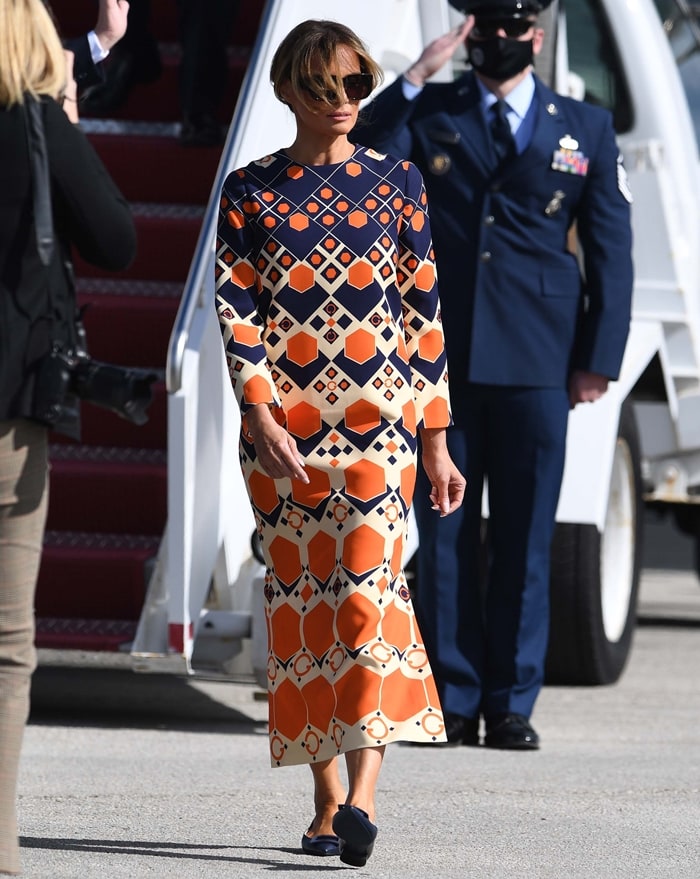 Melania Trump arrives in Palm Beach wearing a retro-inspired Gucci silk-and-wool cady maxi dress featuring a bold geometric print reminiscent of 1970s psychedelia, paired with understated Roger Vivier goatskin ballerina flats and oversized sunglasses