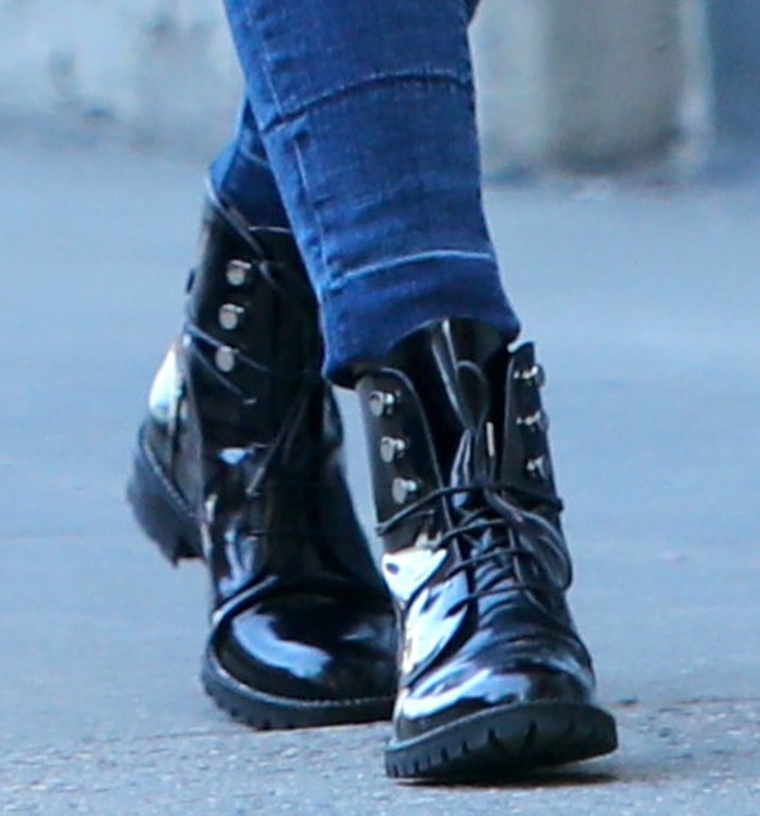 A close-up of Olivia Palermo's glossy Dior Rebelle Army combat boots highlights their polished patent leather, silver-tone studded eyelets, lace-up front, and rugged lug soles