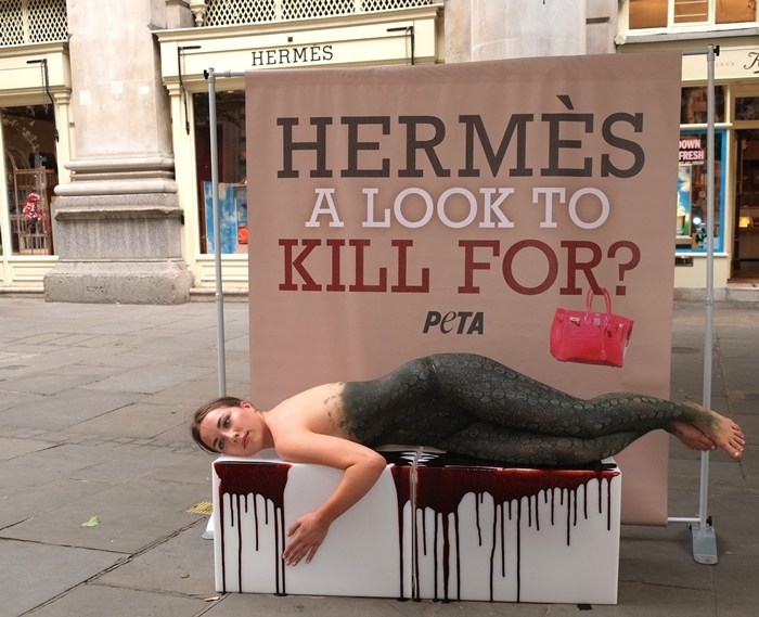 A PETA supporter is body painted to look like a crocodile lying in a pool of blood outside the London Hermès store at The Royal Exchange