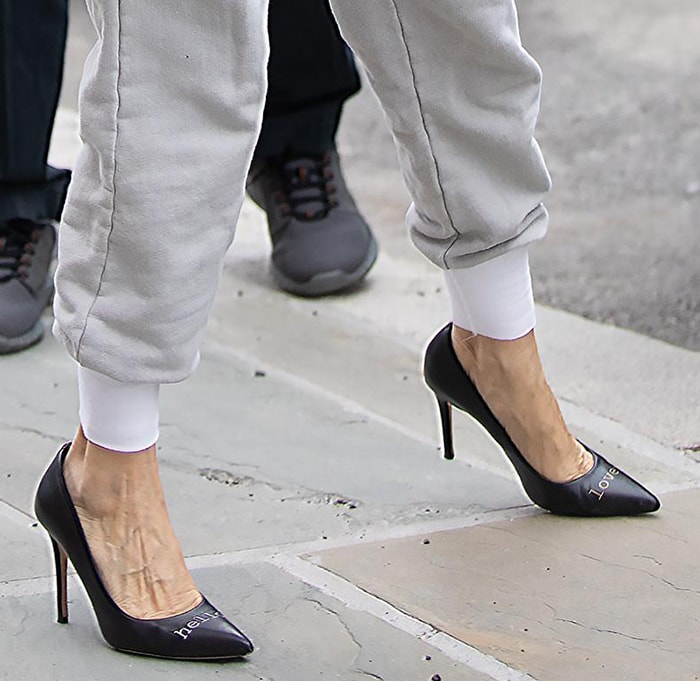 Sarah Jessica Parker’s black SJP “Hello Lover” pumps spell out the playful slogan across their pointed toes, contrasting sharply with her relaxed Pangaia track pants