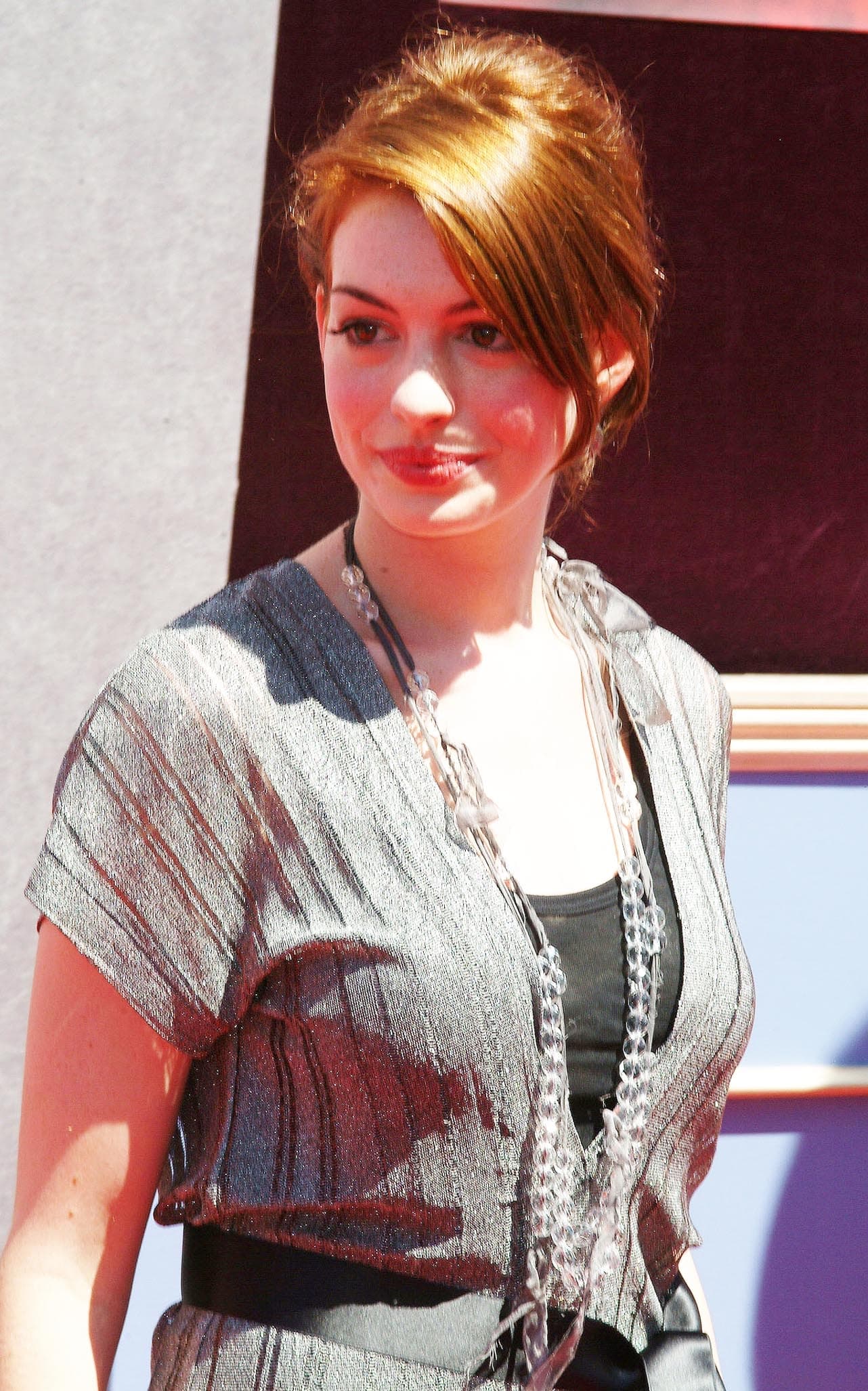 21-year-old Anne Hathaway attends the Disney premiere of The Princess Diaries 2: Royal Engagement at Disneyland Resort on August 7, 2004, wearing a shimmering silver dress cinched with a black satin belt and layered with crystal bead necklaces