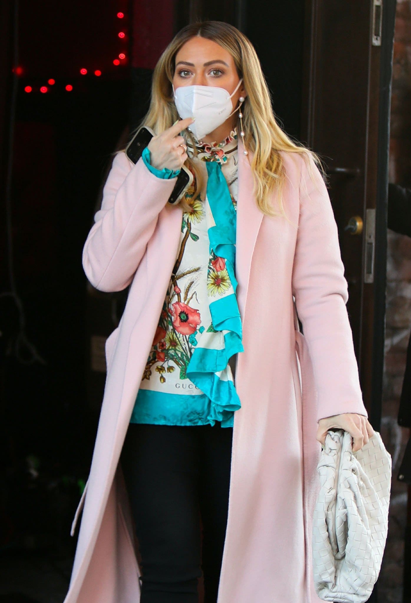Hilary Duff completes Kelsey Peters' feminine Younger wardrobe with long pearl drop earrings, a woven white Bottega Veneta pouch, and a romantic Gucci poppies blouse layered beneath a tailored blush coat