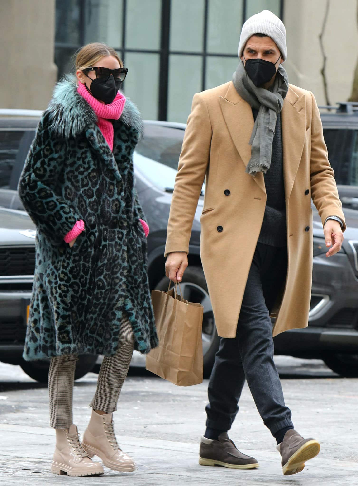 Johannes Huebl complements Olivia Palermo's statement winter look in a camel double-breasted overcoat layered over a charcoal knit and gray scarf