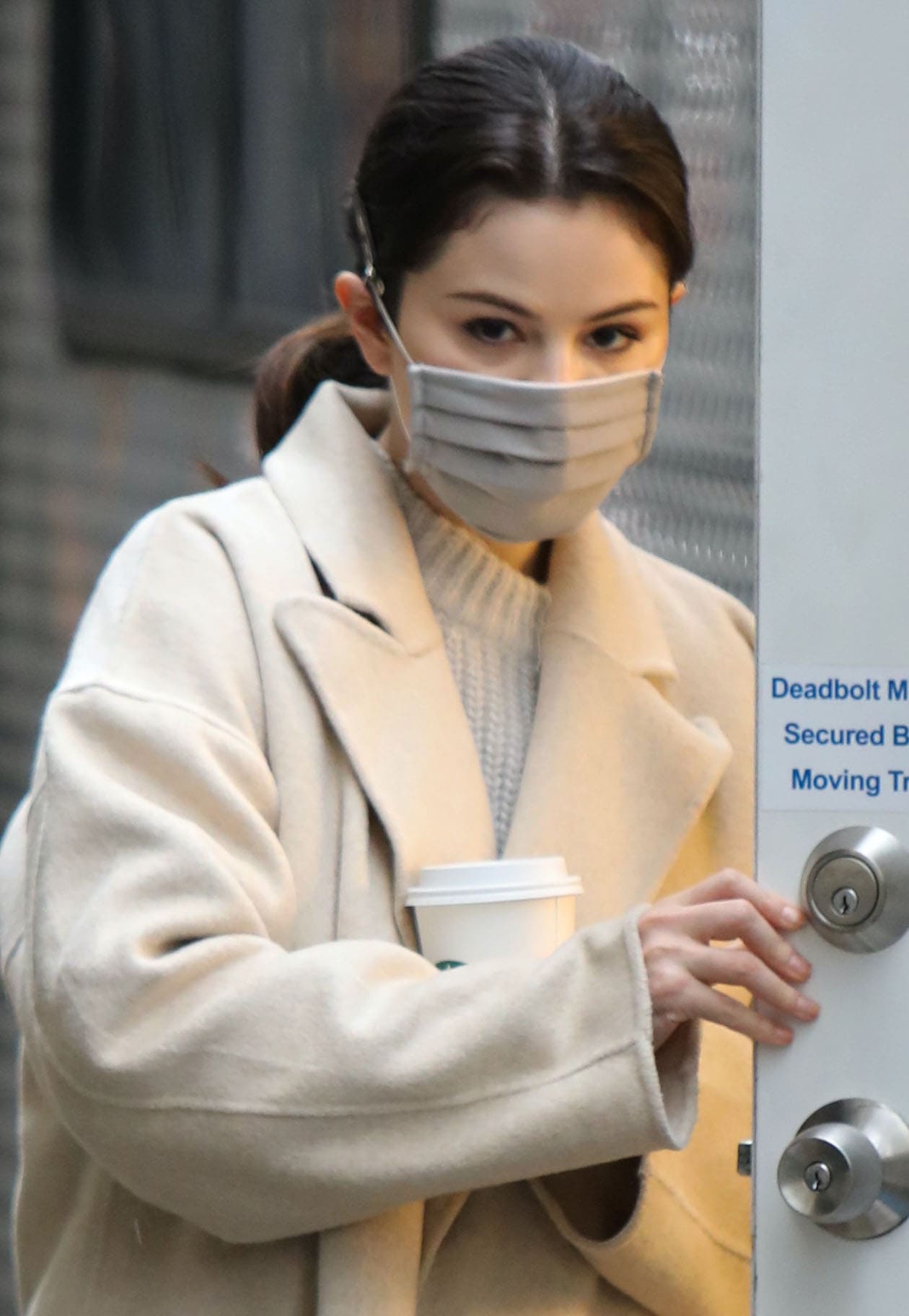 The actress keeps a low profile between takes, her sleek ponytail and neutral face mask adding a polished touch to her soft knit-and-wool ensemble